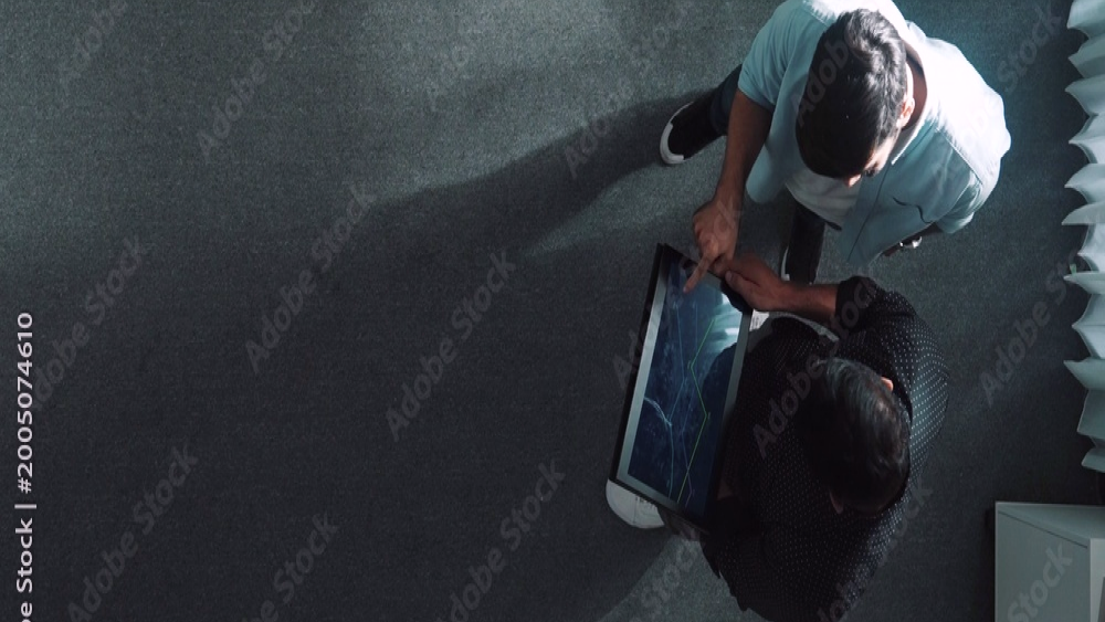 Two professionals reviewing analytics on a tablet from above in an office