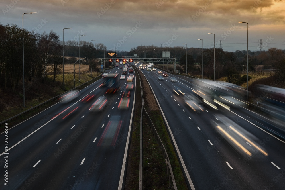 Motion-blurred traffic on a multi-lane motorway with a guardrail in the foreground