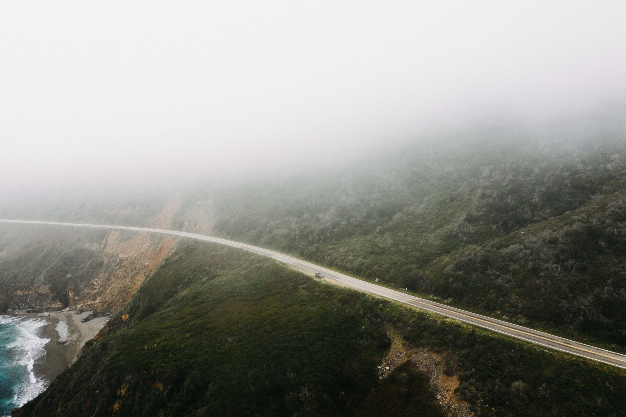 Coastal road winding along a foggy clifftop above the ocean