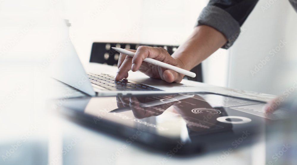 Hands using a stylus on a tablet displaying business analytics charts